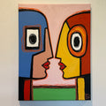 Abstract painting with colorful shapes and a face-like design on a beige wall.